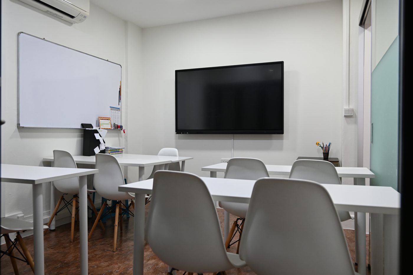 Bright, tidy classroom with a wall-mounted screen